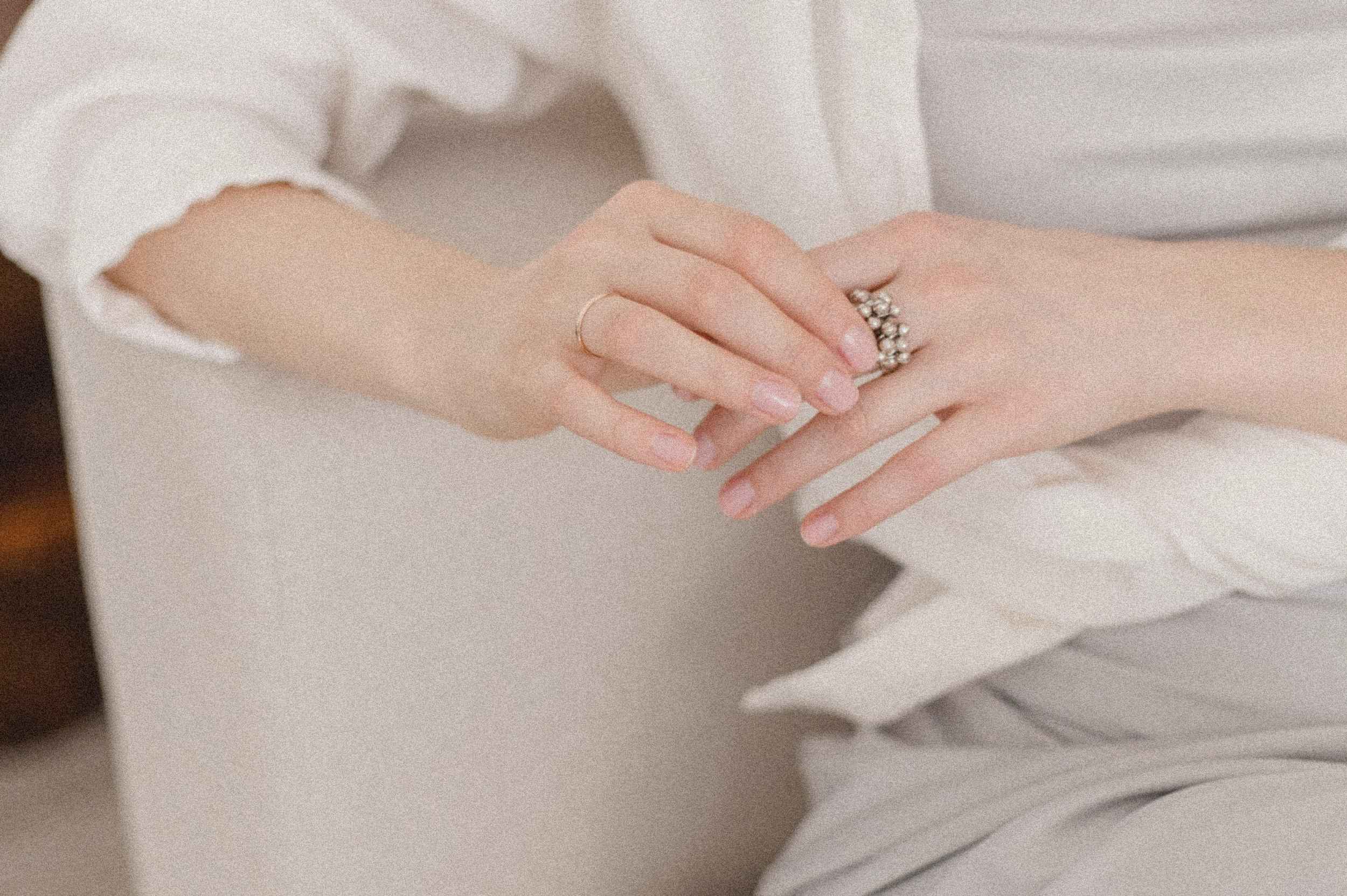 Berufsfindung als junge Frau1 Detailaufnahme einer Frau in heller Kleidung, die gedankenverloren ihre Hände betrachtet – Symbolbild für die Berufsfindung als junge Frau.