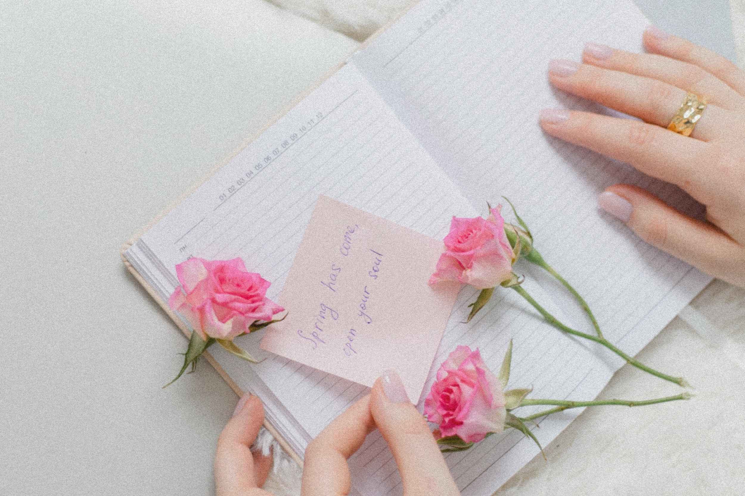 Website Texte schreiben lassen Zwei Hände über einem offenen Notizbuch mit zartrosa Rosen und einer Notiz – inspiriert vom Gedanken, Website Texte schreiben zu lassen und den eigenen Worten Raum zu geben.</p>
<p>