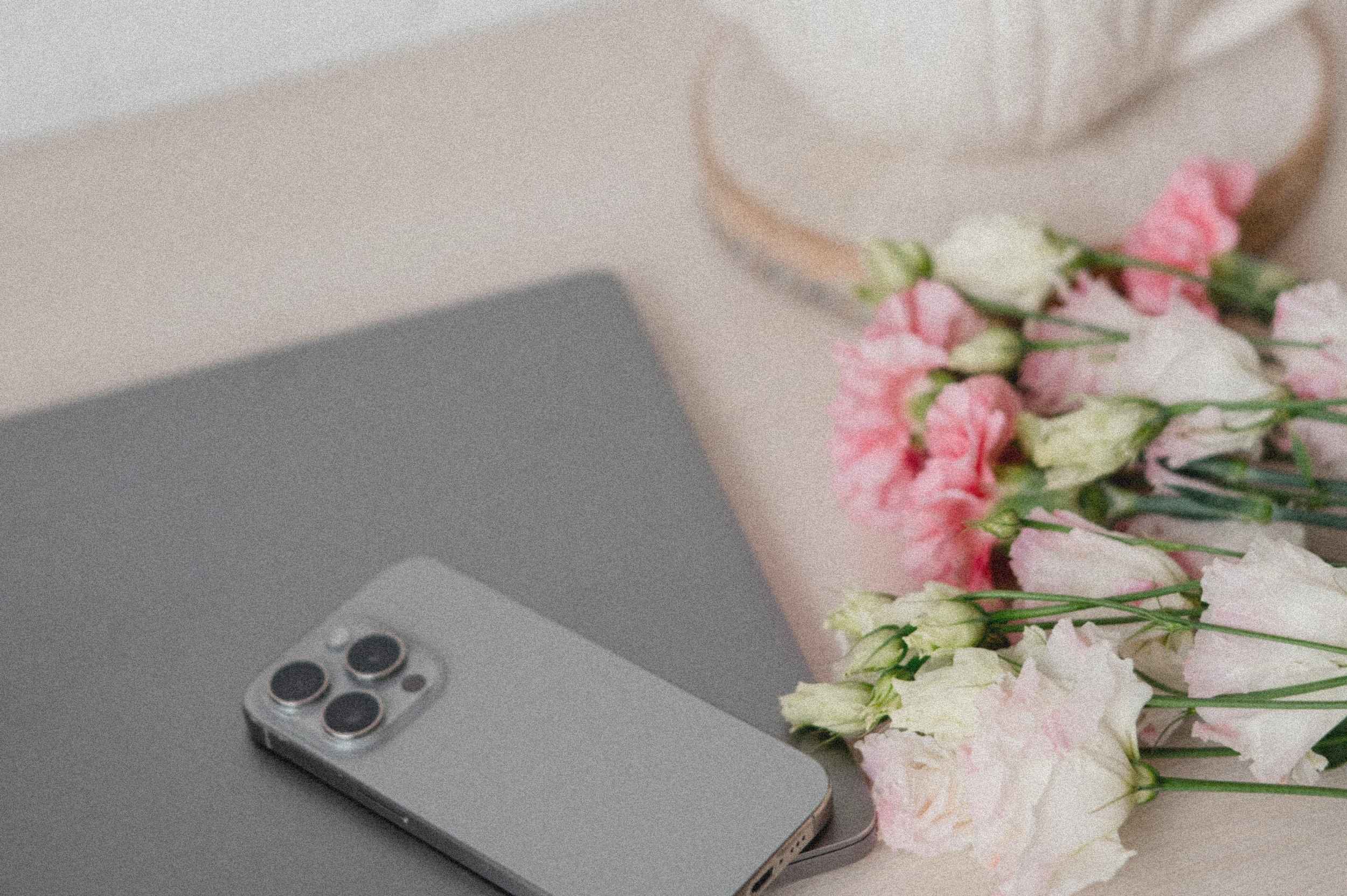 mehrsprachige Website erstellen1 Smartphone, Laptop und frische Blumen auf einem Schreibtisch – inspirierende Arbeitsatmosphäre für alle, die eine mehrsprachige Website erstellen.